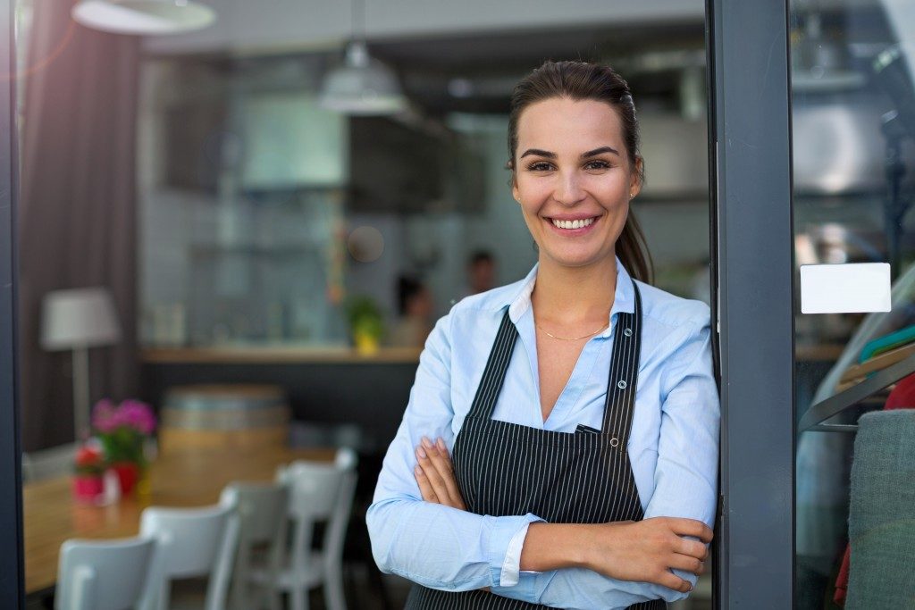 woman leaning against the door of her restaurant